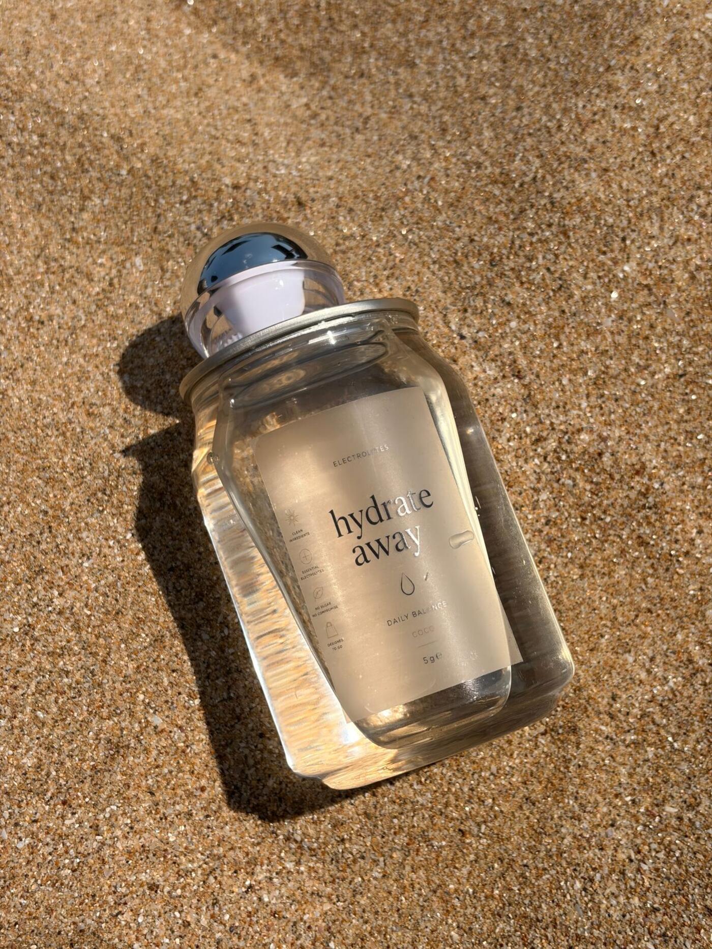 A Hydrate away can lying on golden sand in the sun